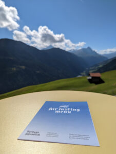 A printed air-tasting menu on a table overlooking a beautiful mountain landscape